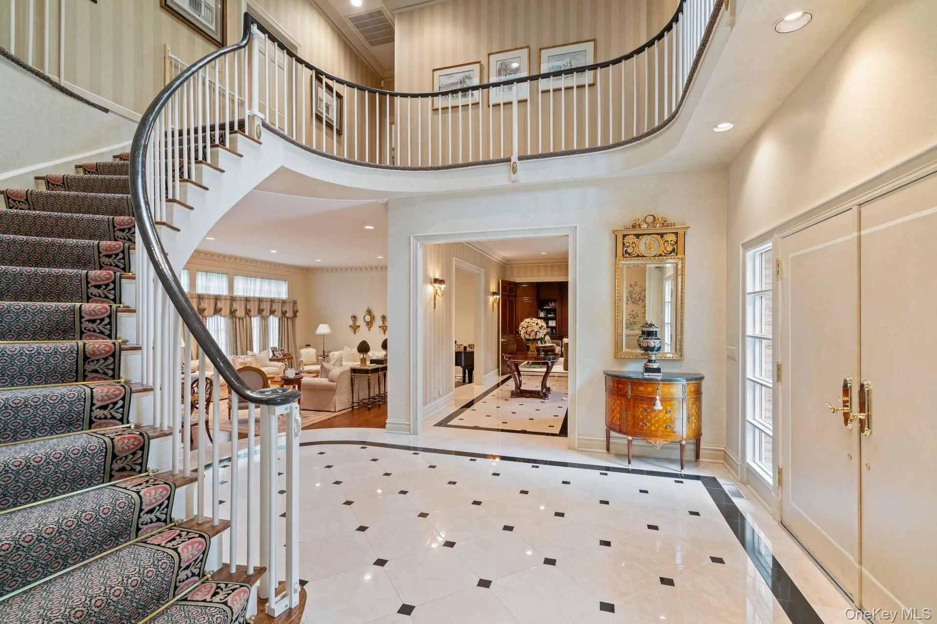 Grand entrance foyer with inlaid marble floors, recessed lighting sweeping staircase to upper level Grand entrance foyer with inlaid marble floors, recessed lighting sweeping staircase to upper level