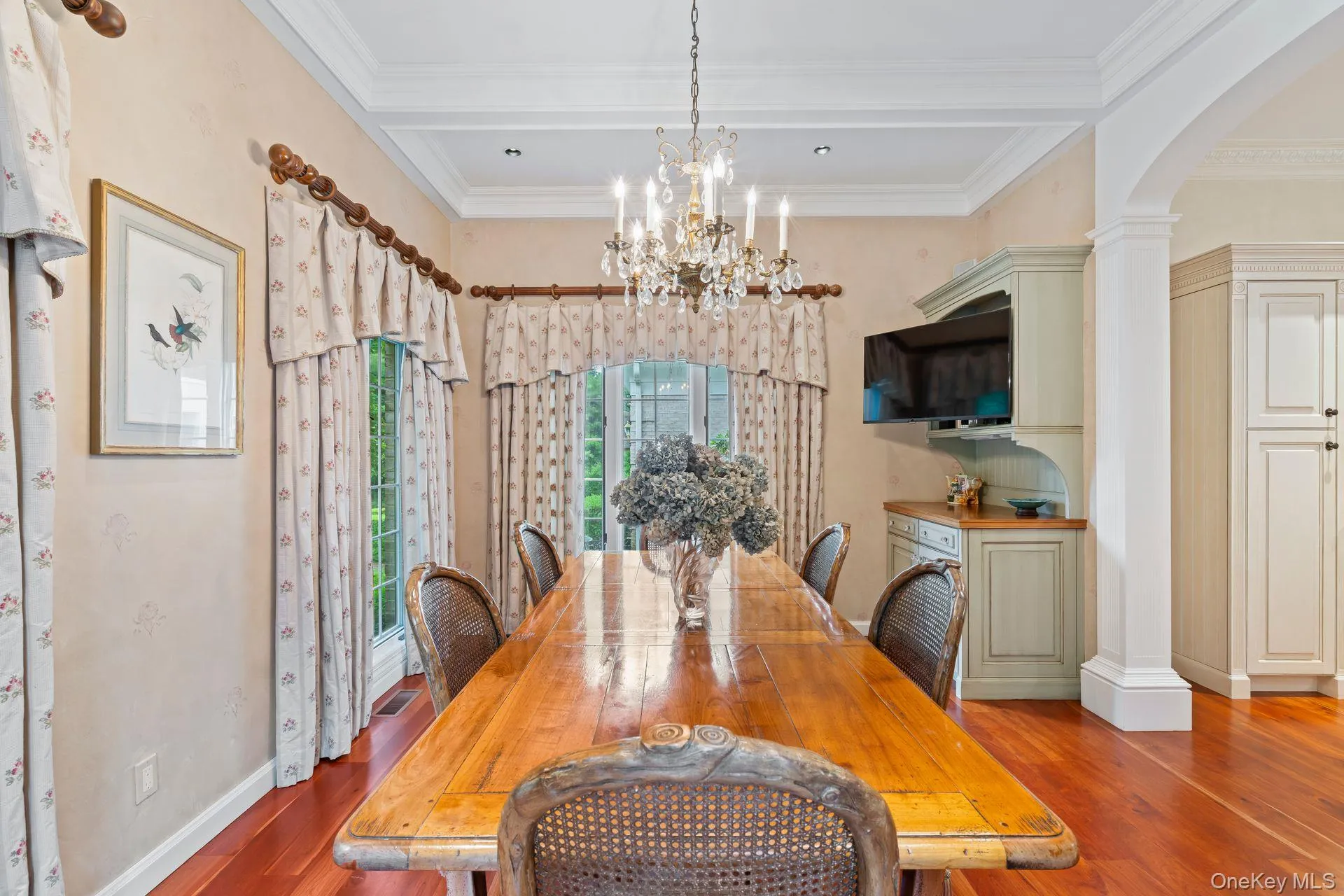 Dining space featuring arched walkways, wood finished floors, a chandelier, decorative columns, and ornamental molding Dining space featuring arched walkways, wood finished floors, a chandelier, decorative columns, and ornamental molding