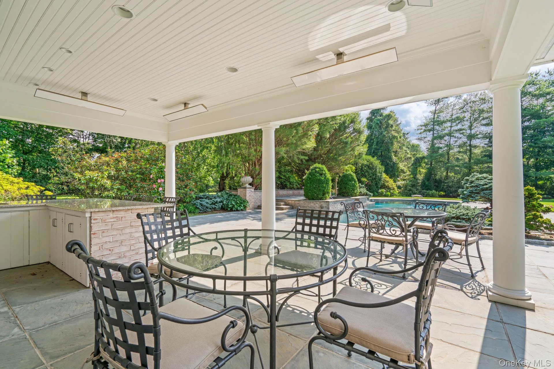 View of patio / terrace with an outdoor pool, outdoor dining area, a ceiling fan, and view of wooded area View of patio / terrace with an outdoor pool, outdoor dining area, a ceiling fan, and view of wooded area