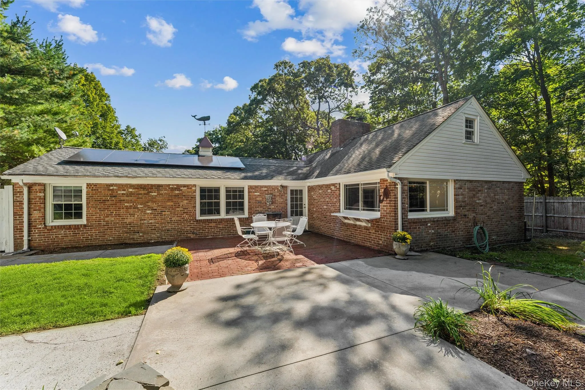 Brick exterior home with solar panels, a gabled roofline, and a cupola with a weather vane Brick exterior home with solar panels, a gabled roofline, and a cupola with a weather vane
