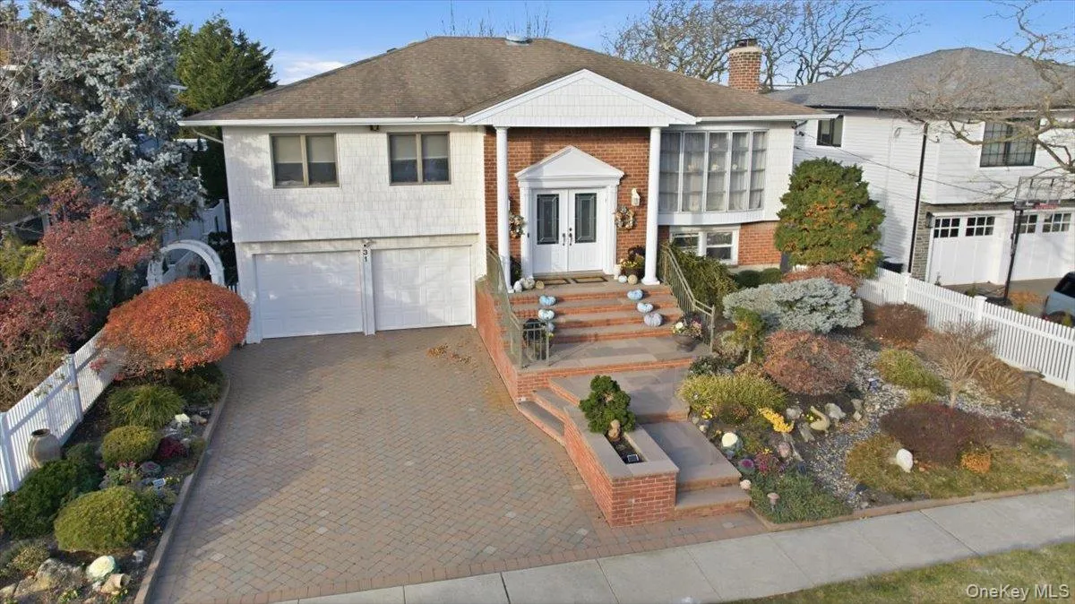 Raised ranch with brick siding, a chimney, decorative driveway, and an attached garage Raised ranch with brick siding, a chimney, decorative driveway, and an attached garage