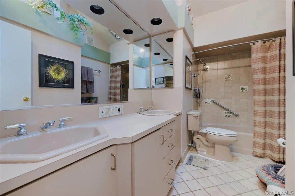 Bathroom with double vanity, light tile patterned flooring, and shower / bath combo Bathroom with double vanity, light tile patterned flooring, and shower / bath combo