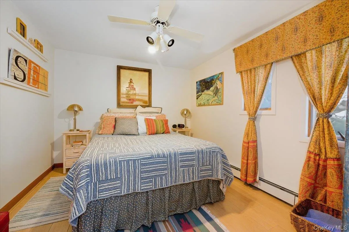 Bedroom featuring light wood-type flooring, ceiling fan, and baseboard heating Bedroom featuring light wood-type flooring, ceiling fan, and baseboard heating
