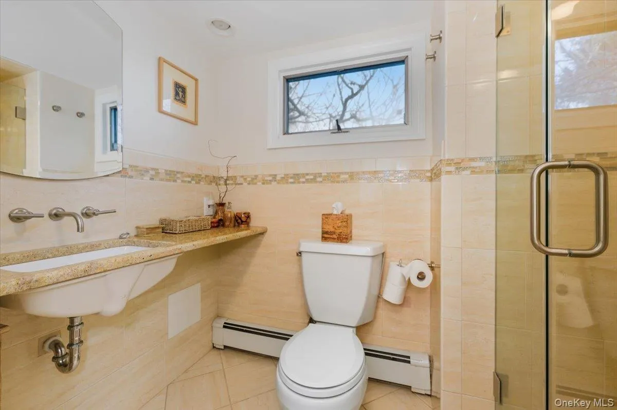 Bathroom featuring a stall shower, a baseboard heating unit, tile patterned flooring, and tile walls Bathroom featuring a stall shower, a baseboard heating unit, tile patterned flooring, and tile walls