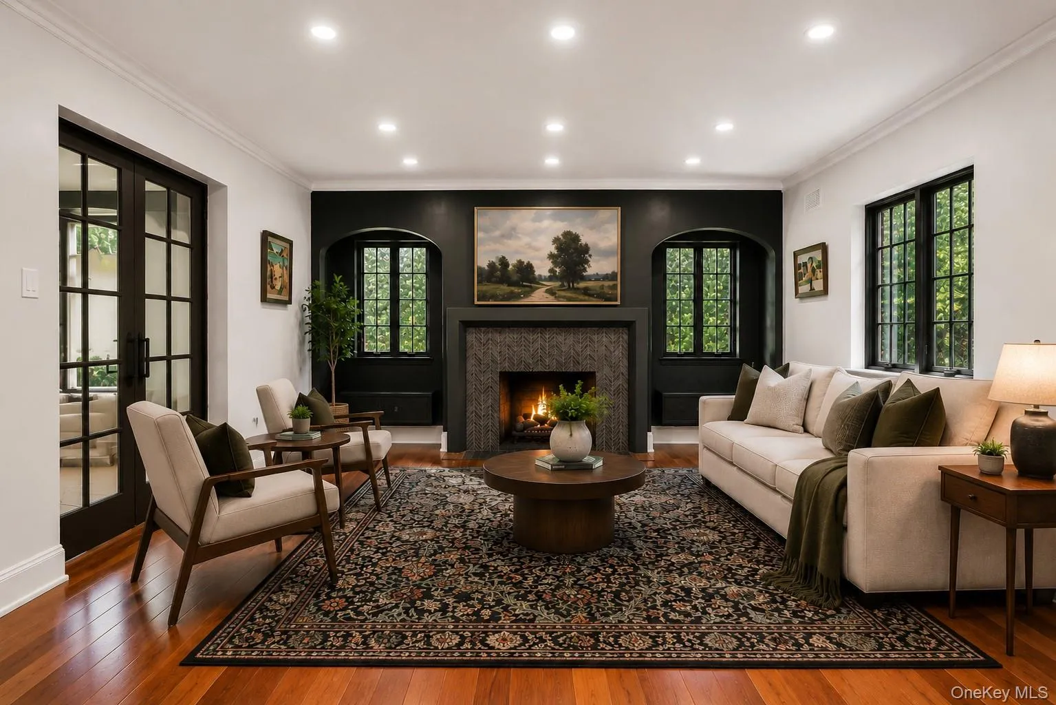 Living room featuring wood-finish flooring, a decorative fireplace with a stone surround, built-in window seating, recessed lighting, and French doors Living room featuring wood-finish flooring, a decorative fireplace with a stone surround, built-in window seating, recessed lighting, and French doors
