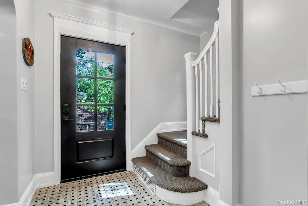 Entryway featuring a paneled door with multiple lites, white trim, and a patterned tile floor Entryway featuring a paneled door with multiple lites, white trim, and a patterned tile floor