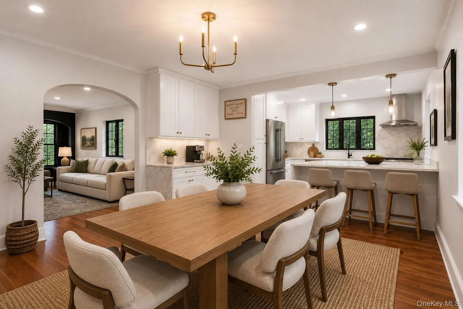 Open-concept dining area with wood-finish flooring and a brass chandelier Open-concept dining area with wood-finish flooring and a brass chandelier