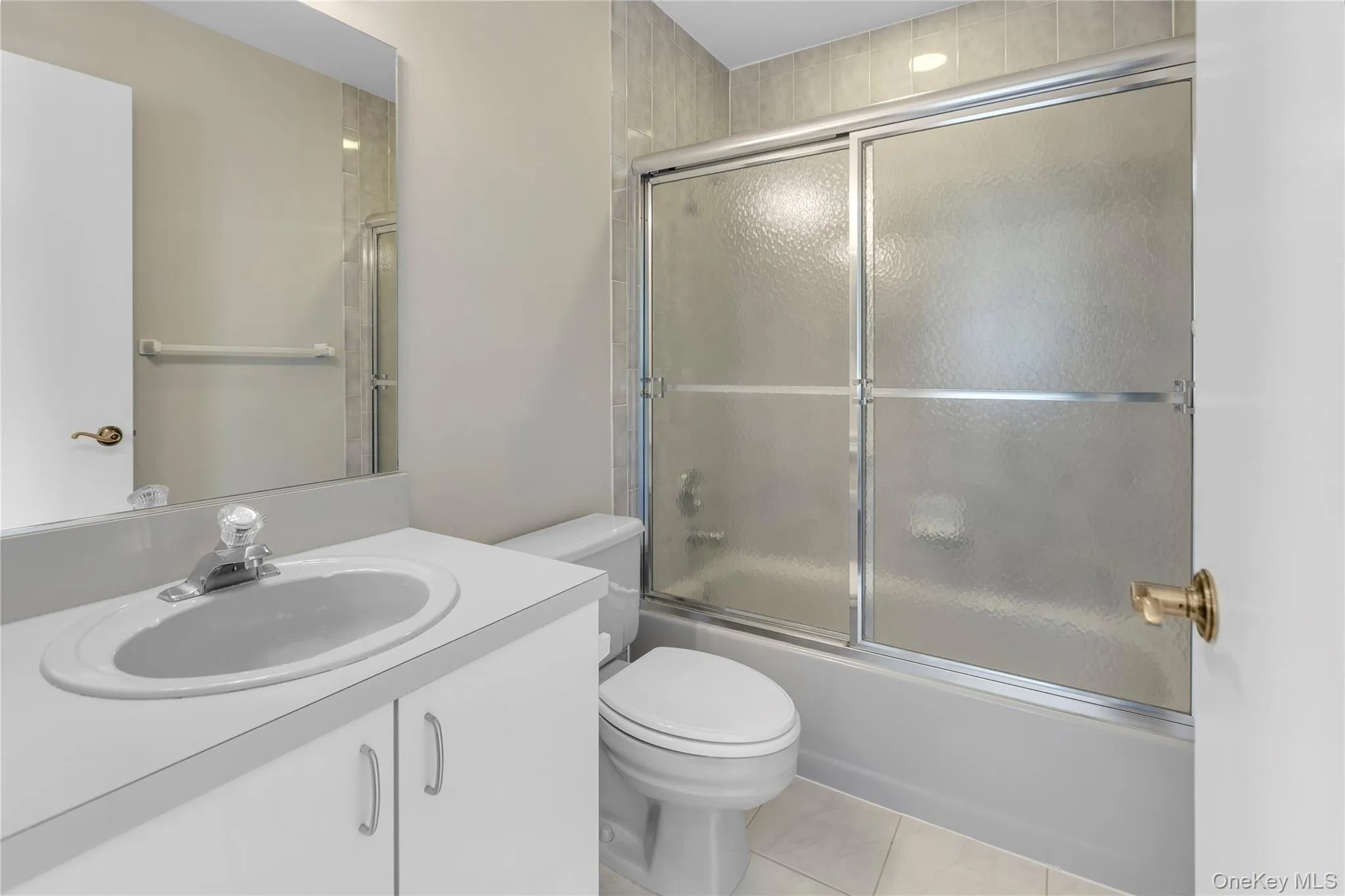 Bathroom featuring a white vanity with integrated sink, chrome faucet, and expansive wall mirror Bathroom featuring a white vanity with integrated sink, chrome faucet, and expansive wall mirror