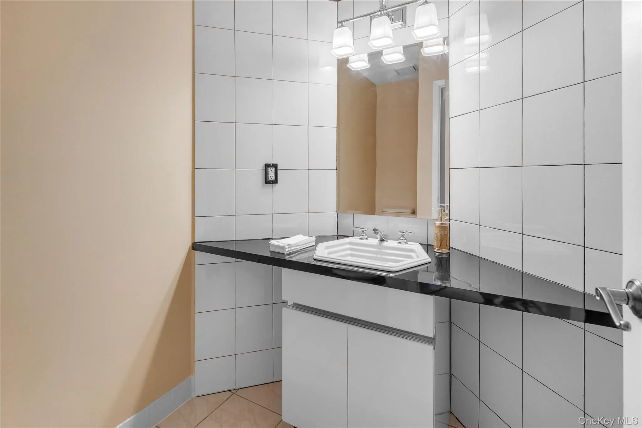Bathroom vanity with a black countertop, white under-sink cabinetry, and a rectangular mirror Bathroom vanity with a black countertop, white under-sink cabinetry, and a rectangular mirror