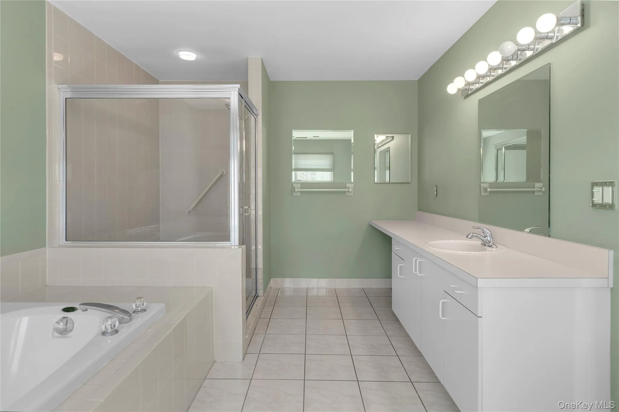 Full vanity with integrated sink, white cabinetry, and a large mirror Full vanity with integrated sink, white cabinetry, and a large mirror