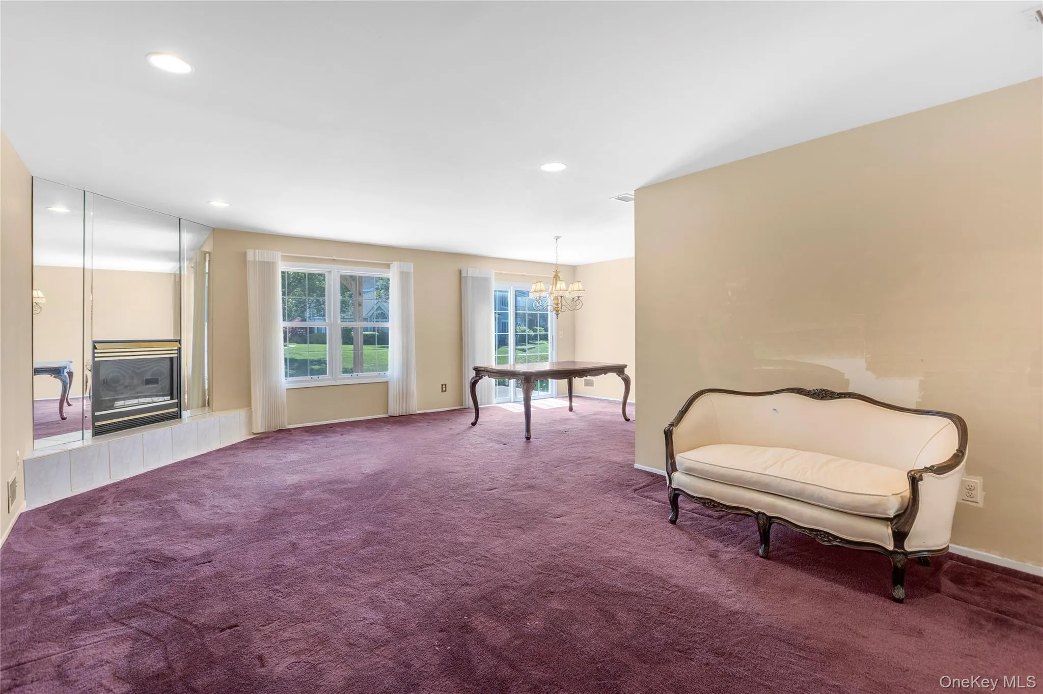 Spacious interior featuring a mirrored fireplace surround, recessed lighting, and large windows with outdoor views Spacious interior featuring a mirrored fireplace surround, recessed lighting, and large windows with outdoor views