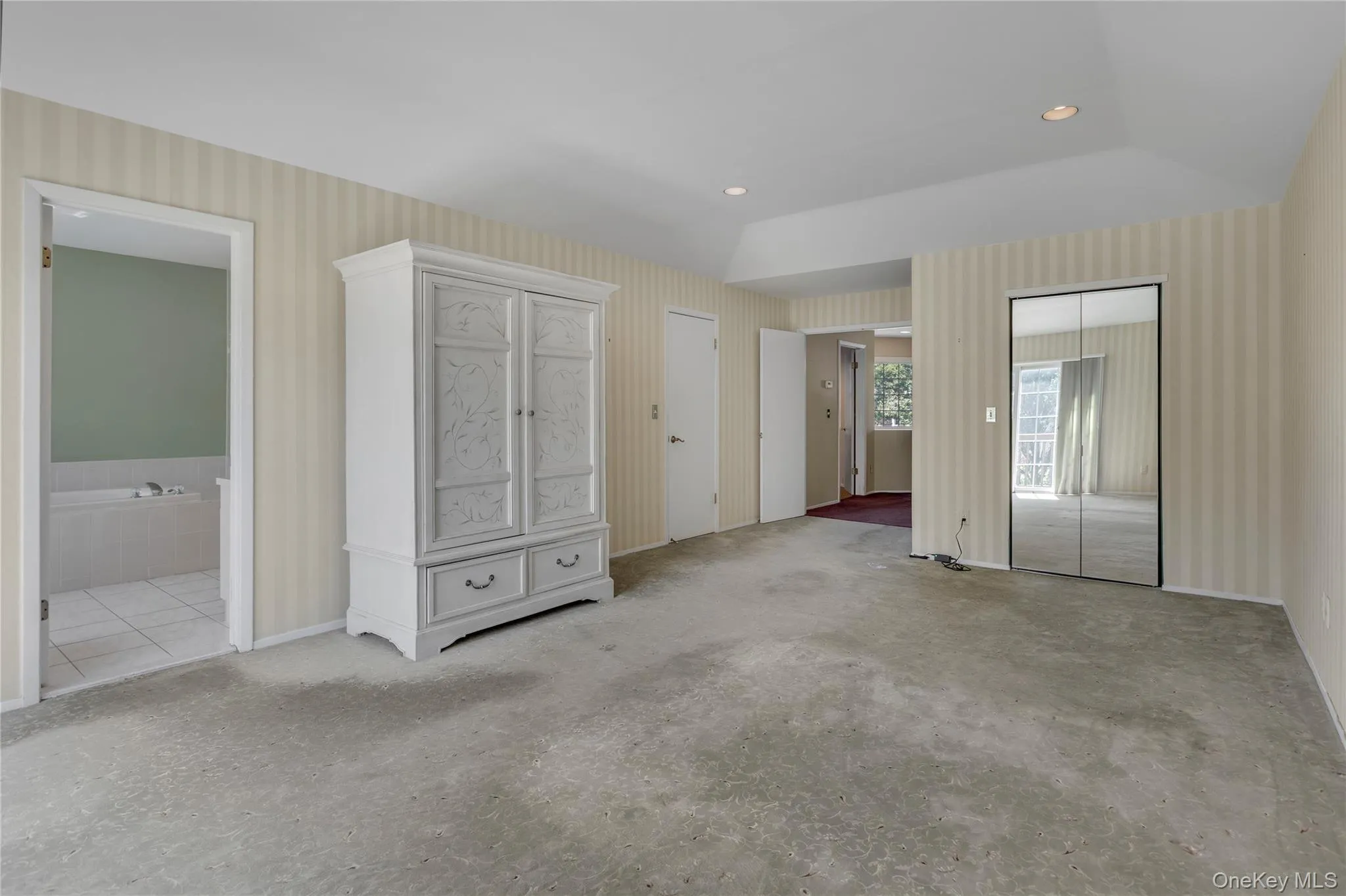 Spacious room featuring patterned wallcovering, recessed lighting, and mirrored closet doors Spacious room featuring patterned wallcovering, recessed lighting, and mirrored closet doors