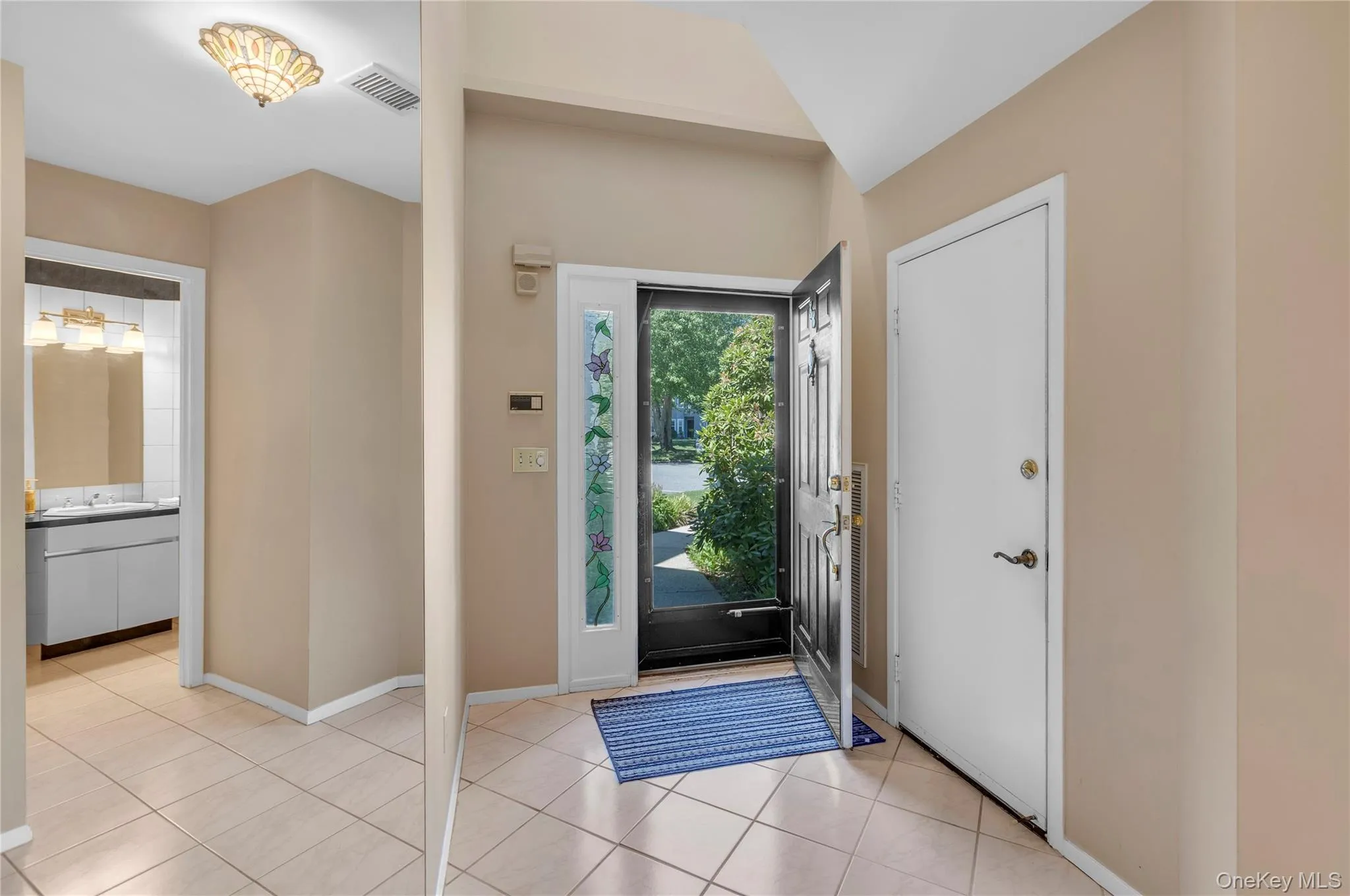 Foyer featuring ceramic tile flooring, a dark entry door with decorative glass sidelites, and a paneled white interior door Foyer featuring ceramic tile flooring, a dark entry door with decorative glass sidelites, and a paneled white interior door