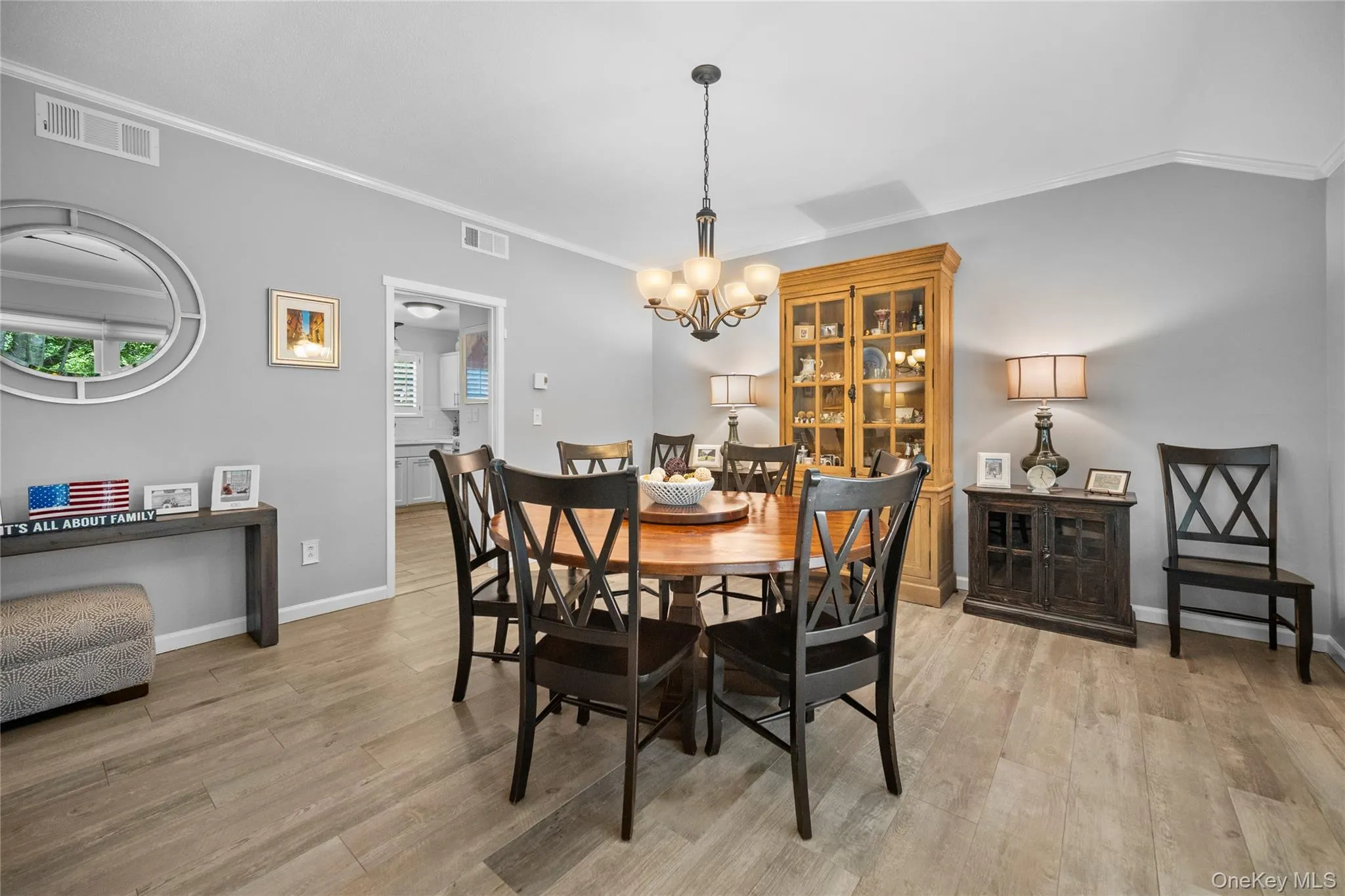 Dining area featuring ceramic flooring, vaulted ceiling, crown molding, a decorative chandelier, and a doorway opening to a kitchen space Dining area featuring ceramic flooring, vaulted ceiling, crown molding, a decorative chandelier, and a doorway opening to a kitchen space