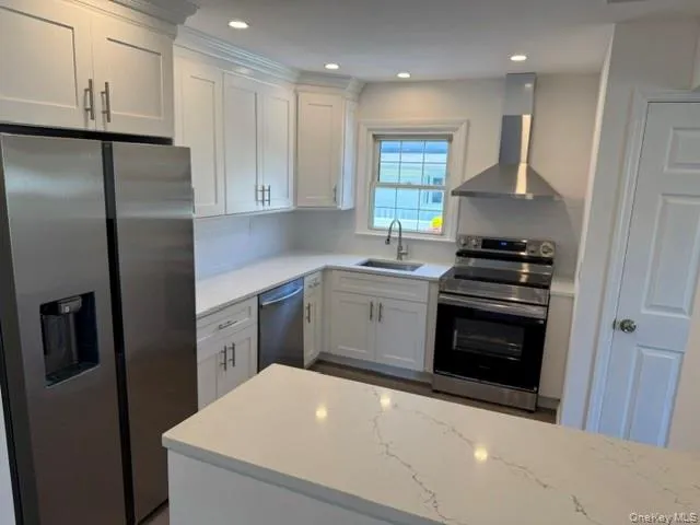 Kitchen featuring white shaker cabinetry, stainless steel appliances, light-toned countertops, a white subway tile backsplash, and recessed lighting Kitchen featuring white shaker cabinetry, stainless steel appliances, light-toned countertops, a white subway tile backsplash, and recessed lighting