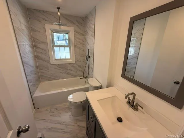 Bathroom featuring a shower/tub combination with full-height tiled surround, rain shower head, and an integrated window Bathroom featuring a shower/tub combination with full-height tiled surround, rain shower head, and an integrated window