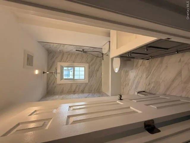 Bathroom featuring marble-look tile flooring and shower surround, a white bathtub, and a dark wood-finish vanity with a light-colored countertop Bathroom featuring marble-look tile flooring and shower surround, a white bathtub, and a dark wood-finish vanity with a light-colored countertop