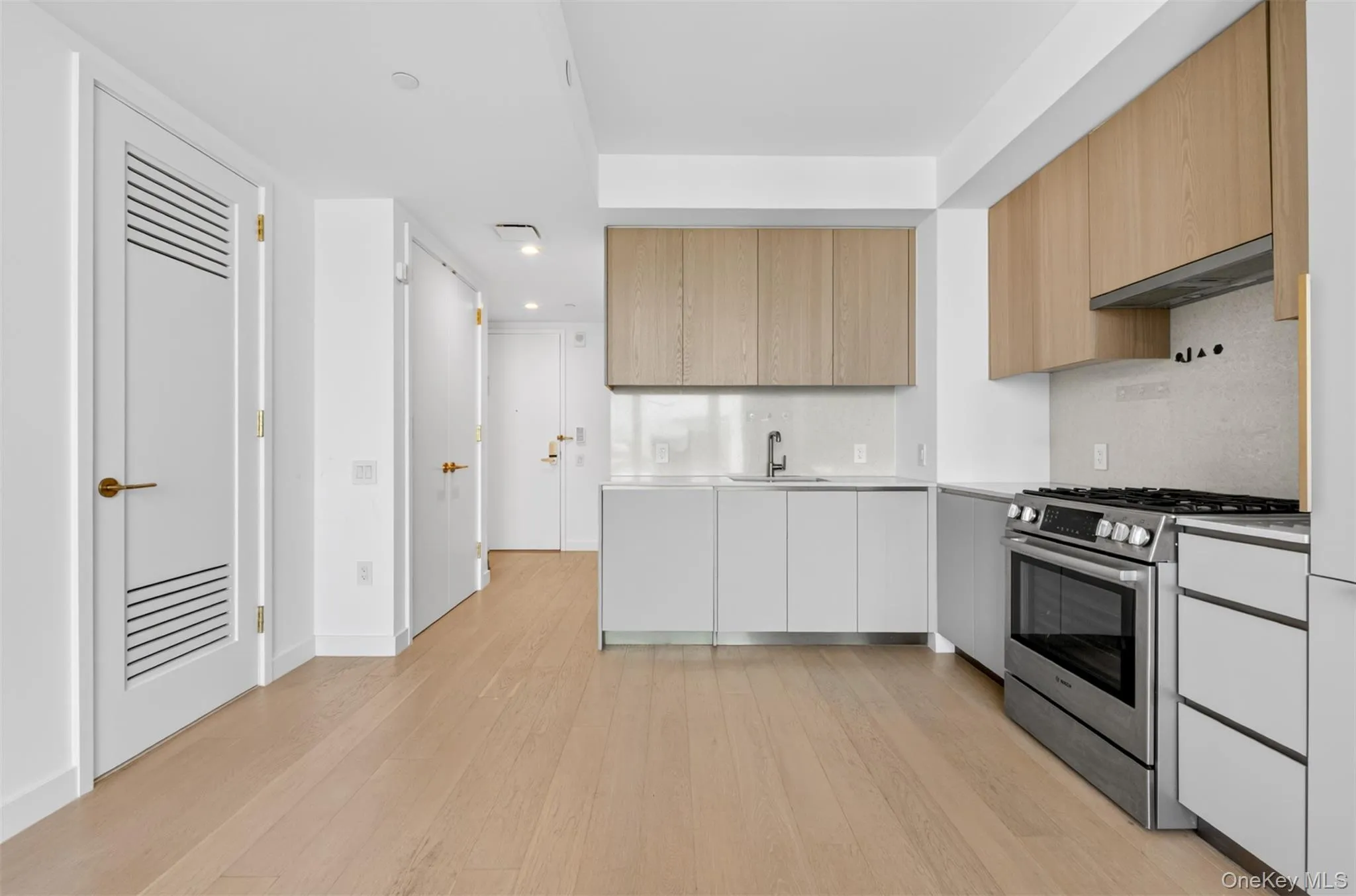 Modern kitchen featuring wood-finish upper cabinetry, white lower cabinetry, and stainless steel appliances Modern kitchen featuring wood-finish upper cabinetry, white lower cabinetry, and stainless steel appliances