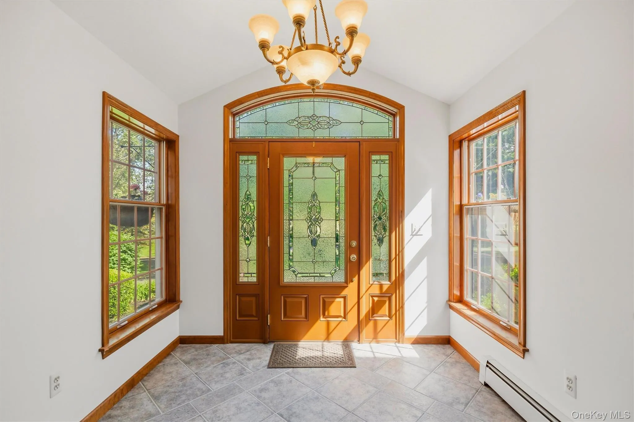 Grand entry featuring a solid wood door with decorative glass inserts, flanked by matching sidelights and an arched transom Grand entry featuring a solid wood door with decorative glass inserts, flanked by matching sidelights and an arched transom