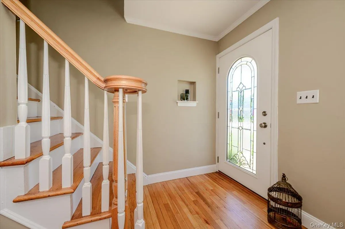 Entryway featuring a decorative leaded glass door, hardwood flooring, and a hardwood staircase with white risers and balusters Entryway featuring a decorative leaded glass door, hardwood flooring, and a hardwood staircase with white risers and balusters