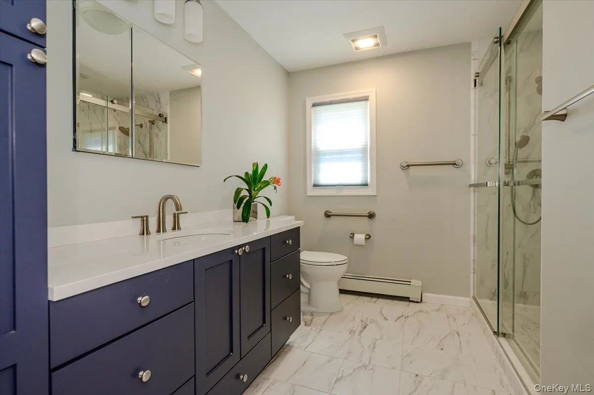 Renovated full bath on main level with modern cabinetry, tile flooring and tile shower with glass doors. Renovated full bath on main level with modern cabinetry, tile flooring and tile shower with glass doors.