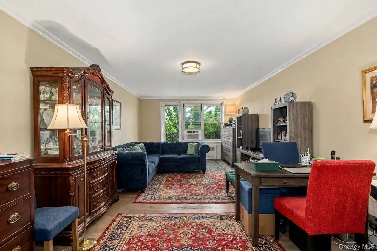Open concept living space featuring a deep blue upholstered sectional, crown molding, and wood-finish flooring. Virtually Enhanced. Open concept living space featuring a deep blue upholstered sectional, crown molding, and wood-finish flooring. Virtually Enhanced.