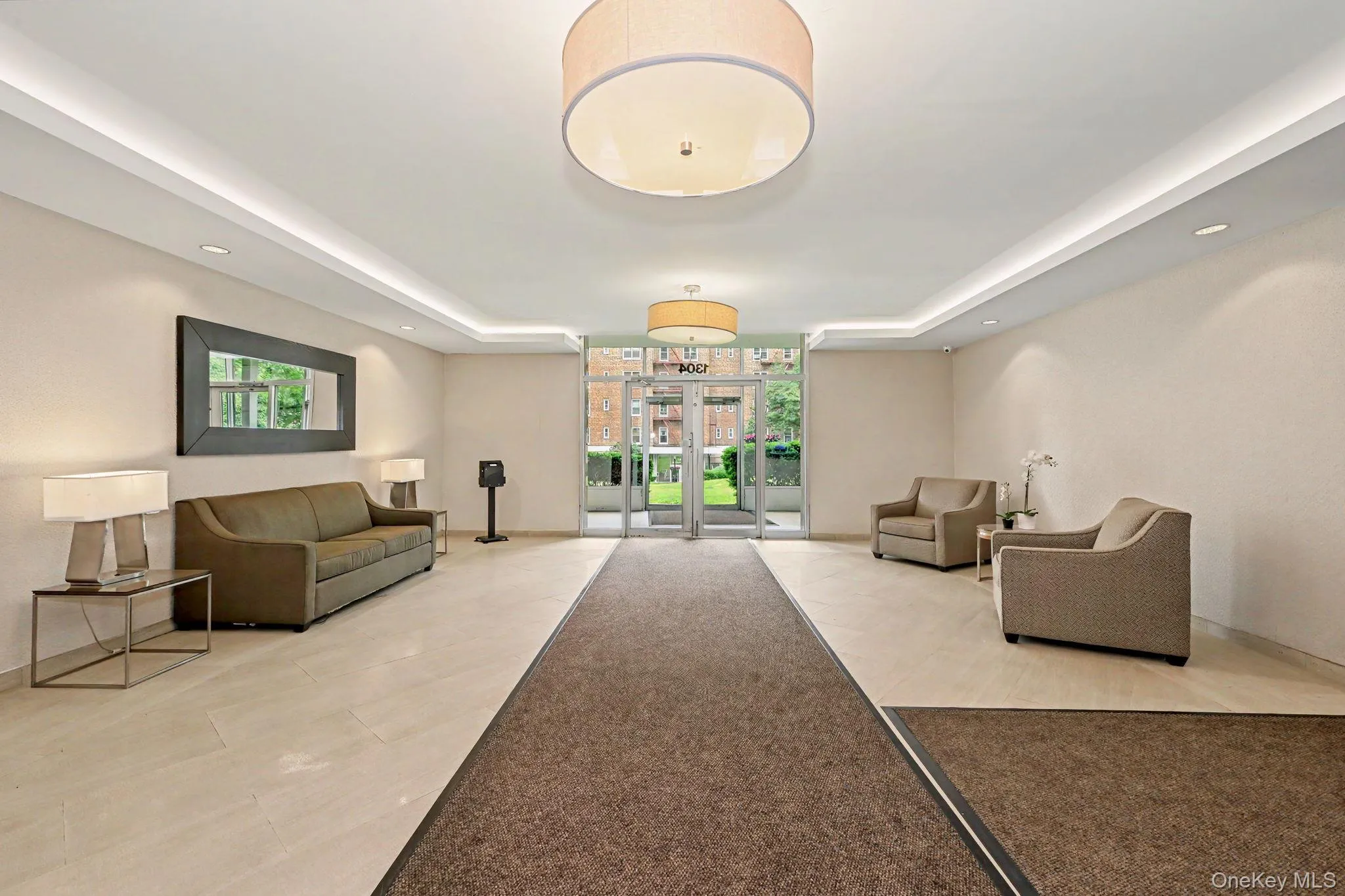 Building entry lobby featuring large format tile flooring, recessed cove lighting, and a drum pendant light fixture Building entry lobby featuring large format tile flooring, recessed cove lighting, and a drum pendant light fixture