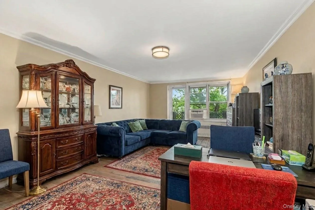 Open concept living space featuring a deep blue upholstered sectional, crown molding, and wood-finish flooring. Virtually Enhanced. Open concept living space featuring a deep blue upholstered sectional, crown molding, and wood-finish flooring. Virtually Enhanced.