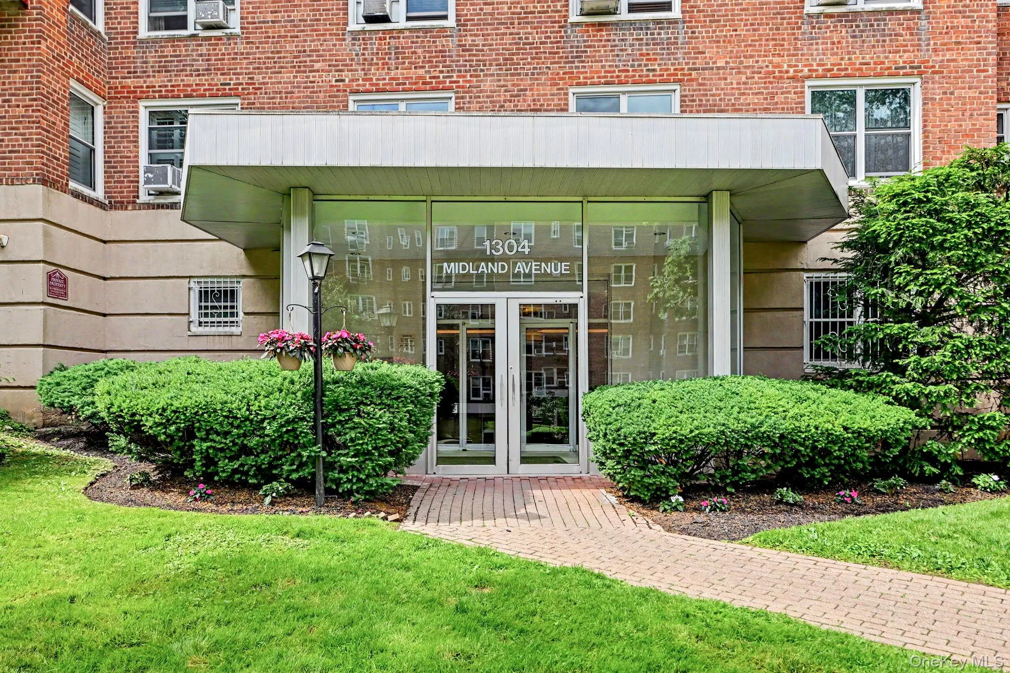 Brick facade building entry featuring a prominent glass-enclosed lobby with double doors Brick facade building entry featuring a prominent glass-enclosed lobby with double doors