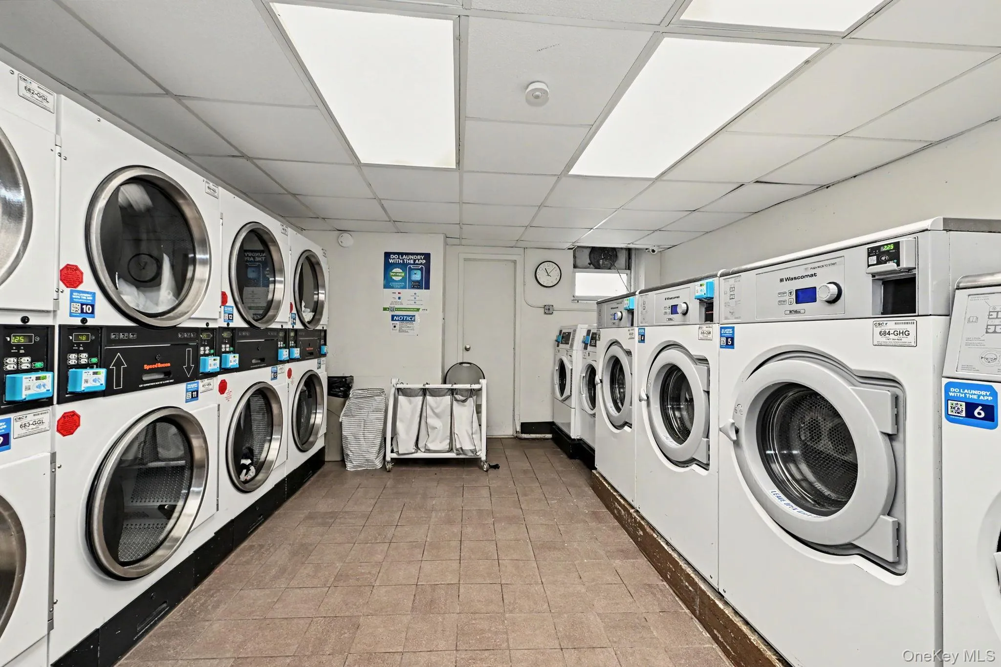 Dedicated laundry room featuring multiple front-loading washing machines and dryers Dedicated laundry room featuring multiple front-loading washing machines and dryers