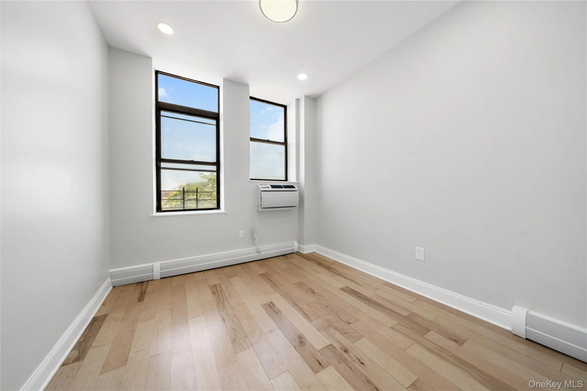 Room featuring wood-finish flooring, white baseboards, and light gray walls Room featuring wood-finish flooring, white baseboards, and light gray walls