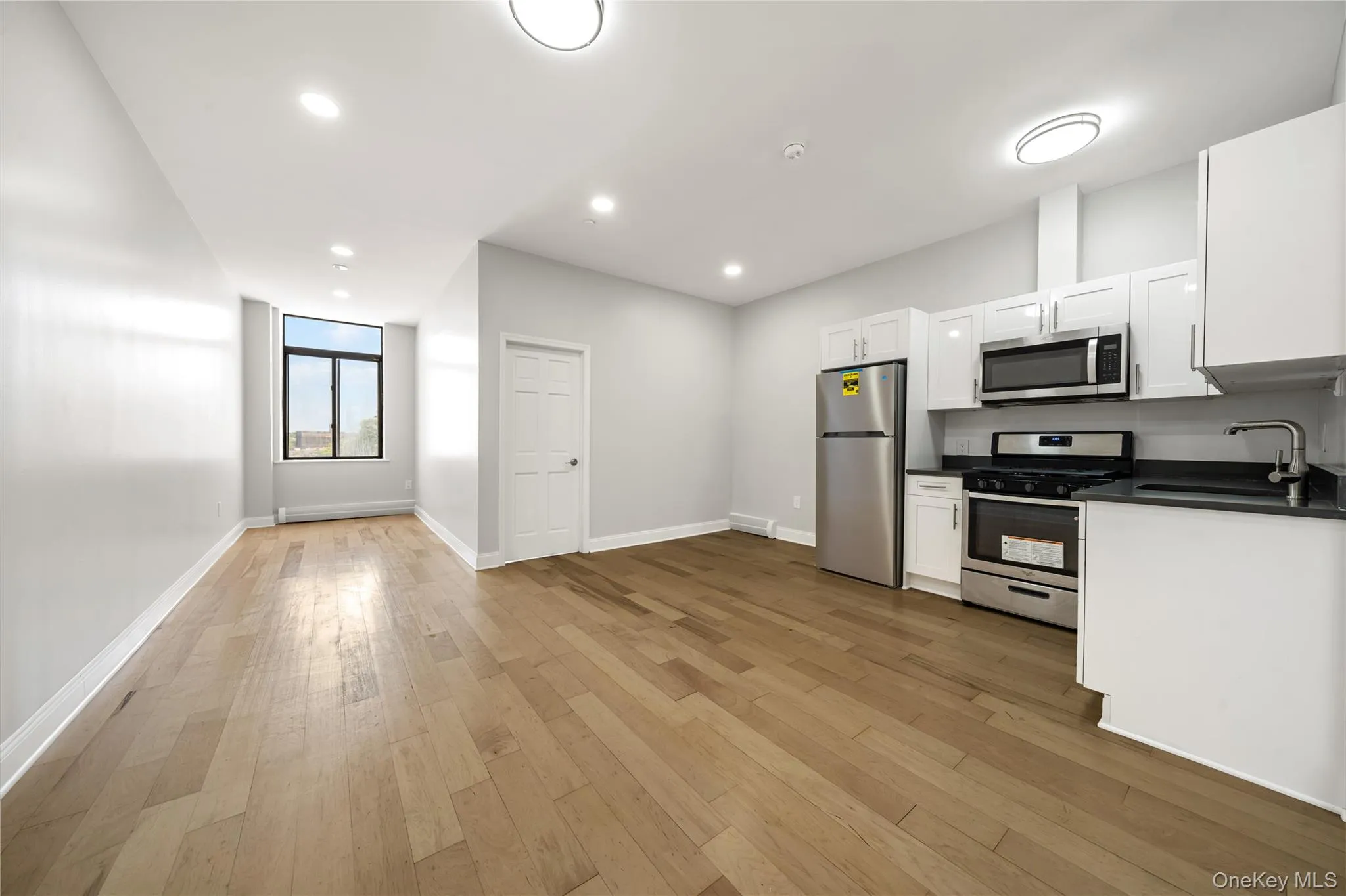 Open-concept living space featuring wood-finish flooring, recessed lighting, and a modern kitchen Open-concept living space featuring wood-finish flooring, recessed lighting, and a modern kitchen