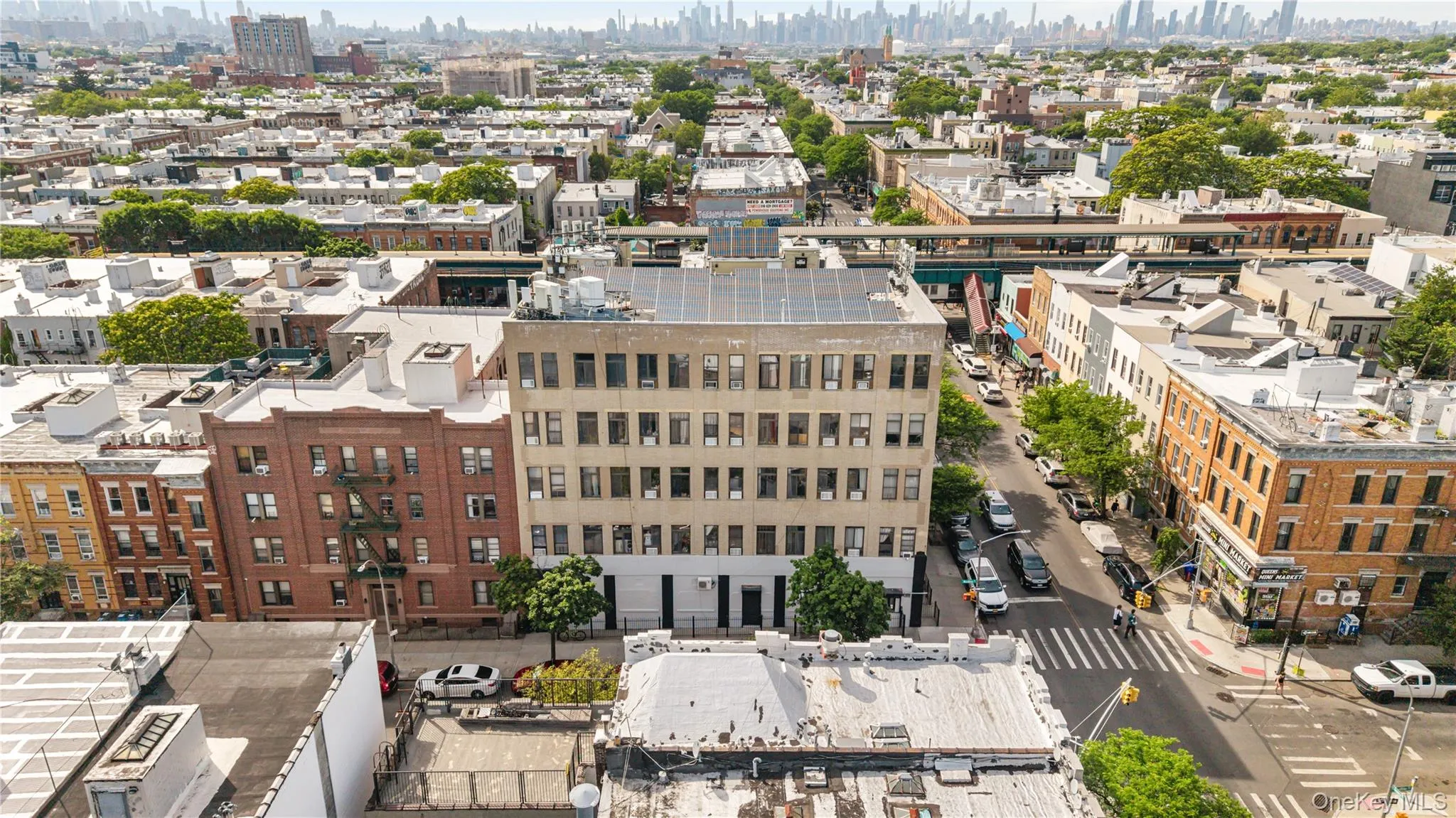 Multi-story building featuring a flat roof with solar panels, a light-colored facade, and multiple rows of rectangular windows Multi-story building featuring a flat roof with solar panels, a light-colored facade, and multiple rows of rectangular windows