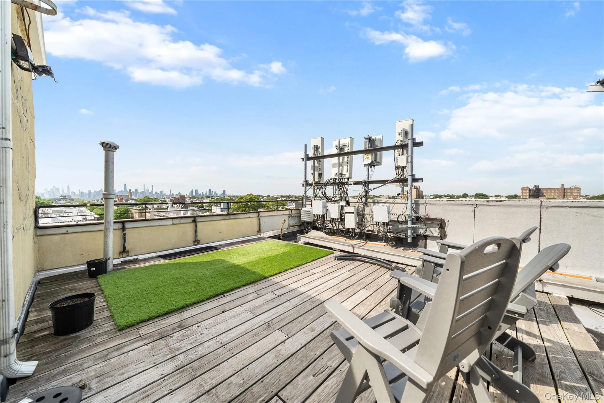 Rooftop deck featuring wood-finish flooring, a green artificial turf area, and a metal railing Rooftop deck featuring wood-finish flooring, a green artificial turf area, and a metal railing
