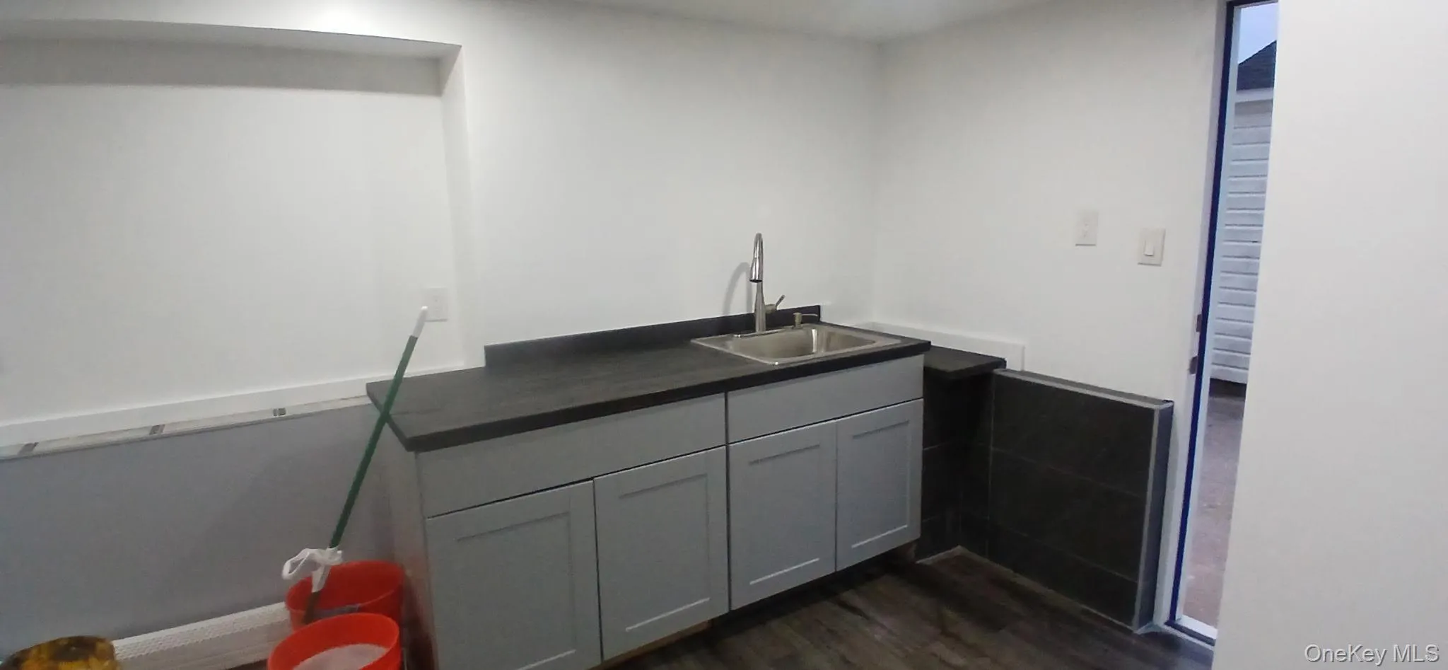 Bar featuring gray cabinetry, dark countertops, and dark wood-style flooring Bar featuring gray cabinetry, dark countertops, and dark wood-style flooring