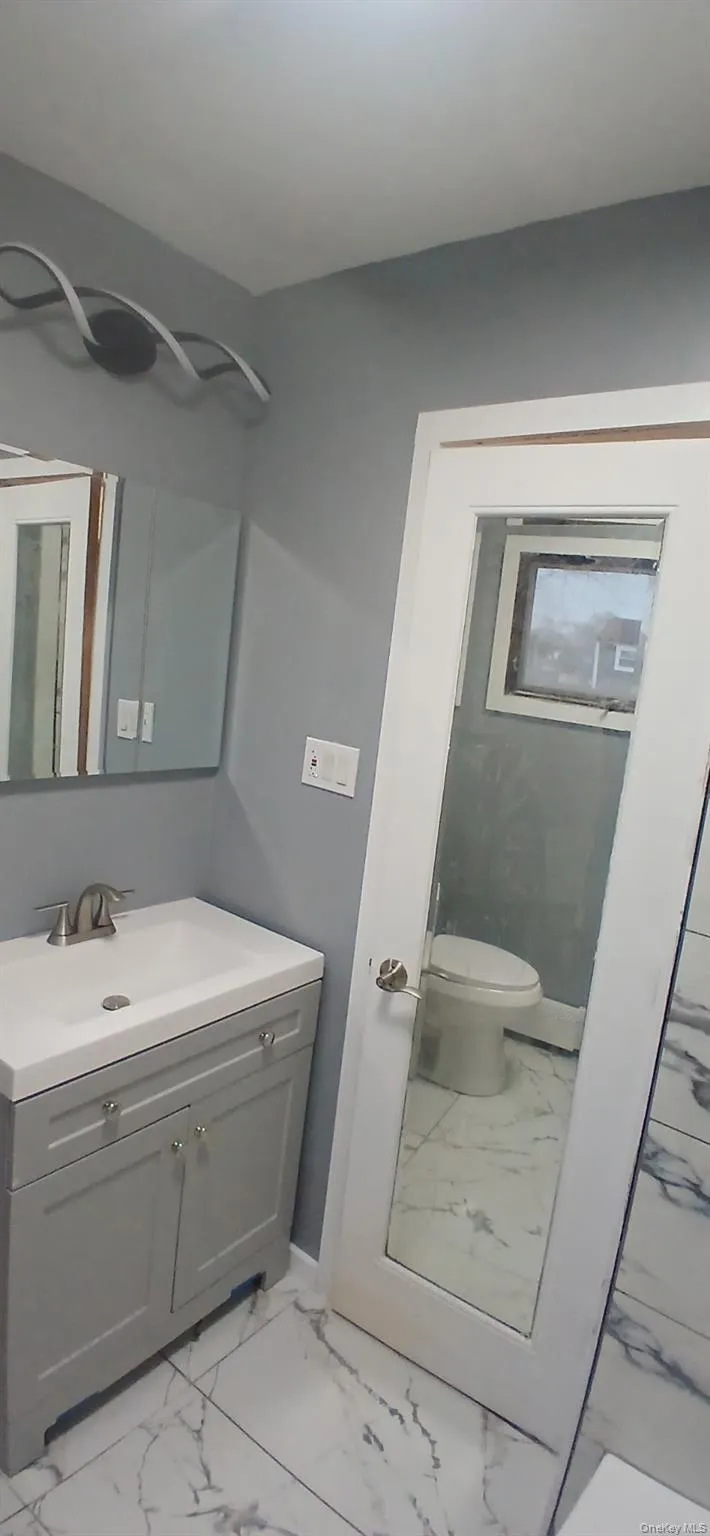 Bathroom featuring light marble finish flooring and vanity Bathroom featuring light marble finish flooring and vanity