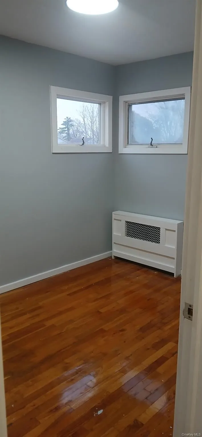 Empty room with hardwood / wood-style flooring and heating unit Empty room with hardwood / wood-style flooring and heating unit