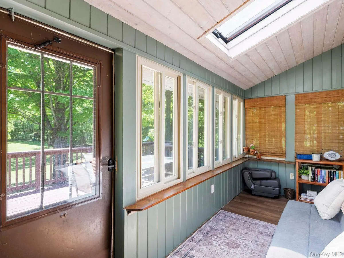 Sunroom featuring a vaulted wood-paneled ceiling, large skylight, and multiple windows Sunroom featuring a vaulted wood-paneled ceiling, large skylight, and multiple windows