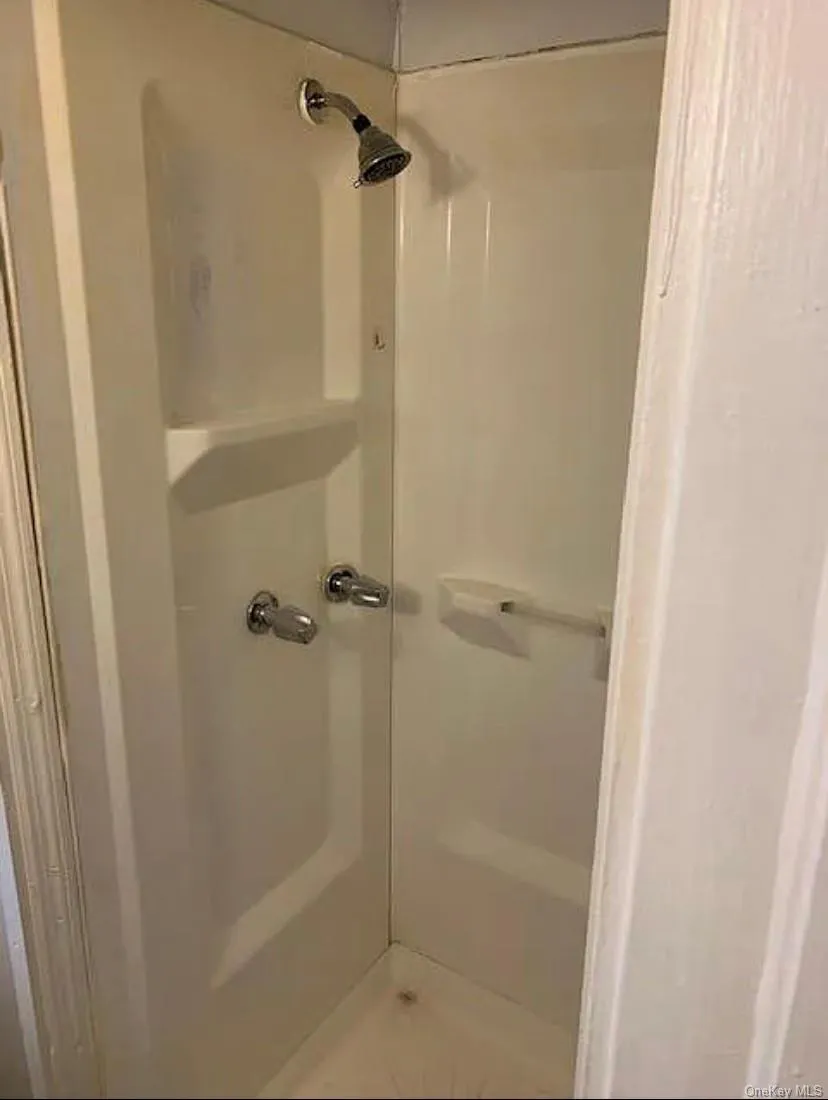 White fiberglass shower stall with integrated shelving and chrome fixtures White fiberglass shower stall with integrated shelving and chrome fixtures