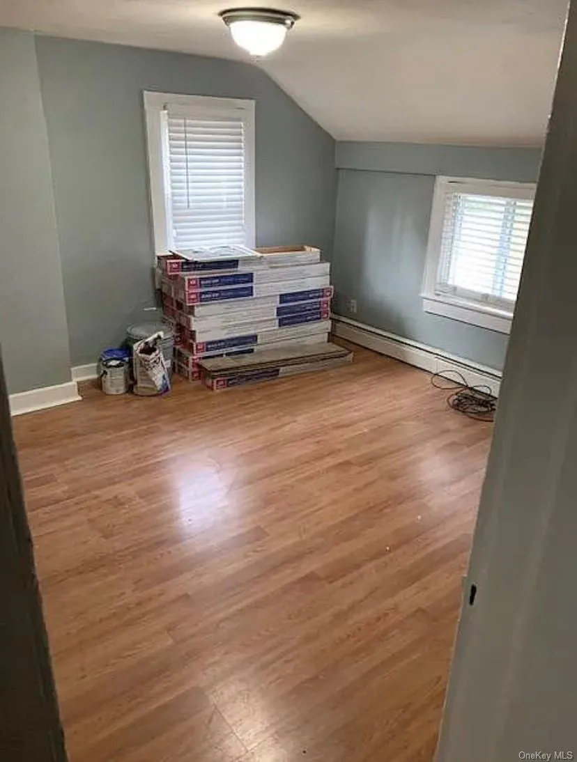Room featuring wood-finish flooring, two windows with white blinds, and a dome ceiling light fixture Room featuring wood-finish flooring, two windows with white blinds, and a dome ceiling light fixture