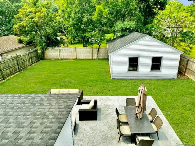 Fenced backyard with an outbuilding, a patio, and view of scattered trees Fenced backyard with an outbuilding, a patio, and view of scattered trees