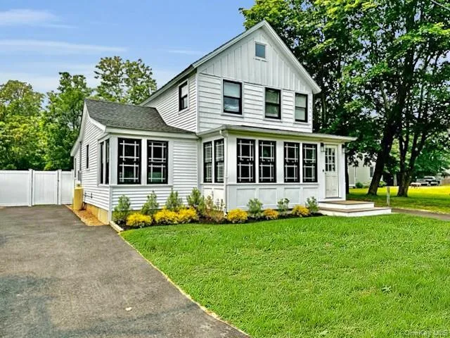 View of front of property with driveway, board and batten siding, a front yard, and a gate View of front of property with driveway, board and batten siding, a front yard, and a gate
