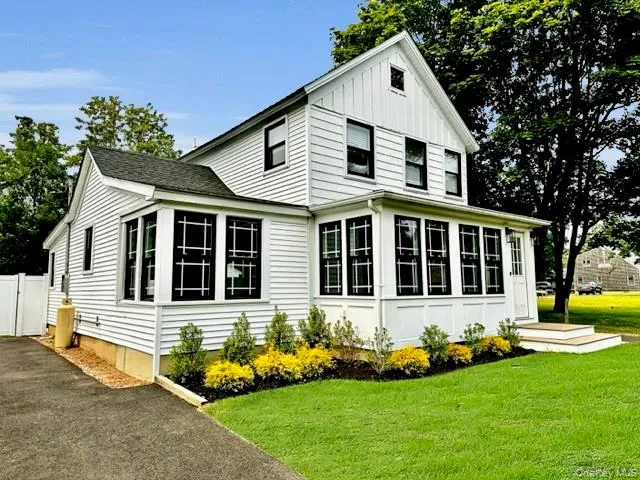 View of property exterior with a yard, asphalt driveway, board and batten siding, and a gate View of property exterior with a yard, asphalt driveway, board and batten siding, and a gate