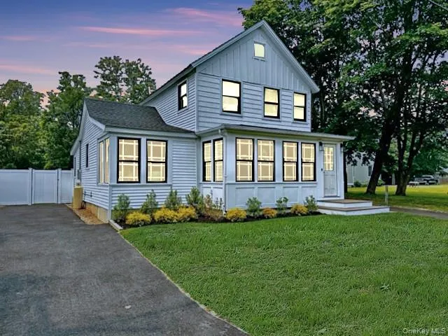 View of front of home with asphalt driveway, board and batten siding, a front yard, and a gate View of front of home with asphalt driveway, board and batten siding, a front yard, and a gate