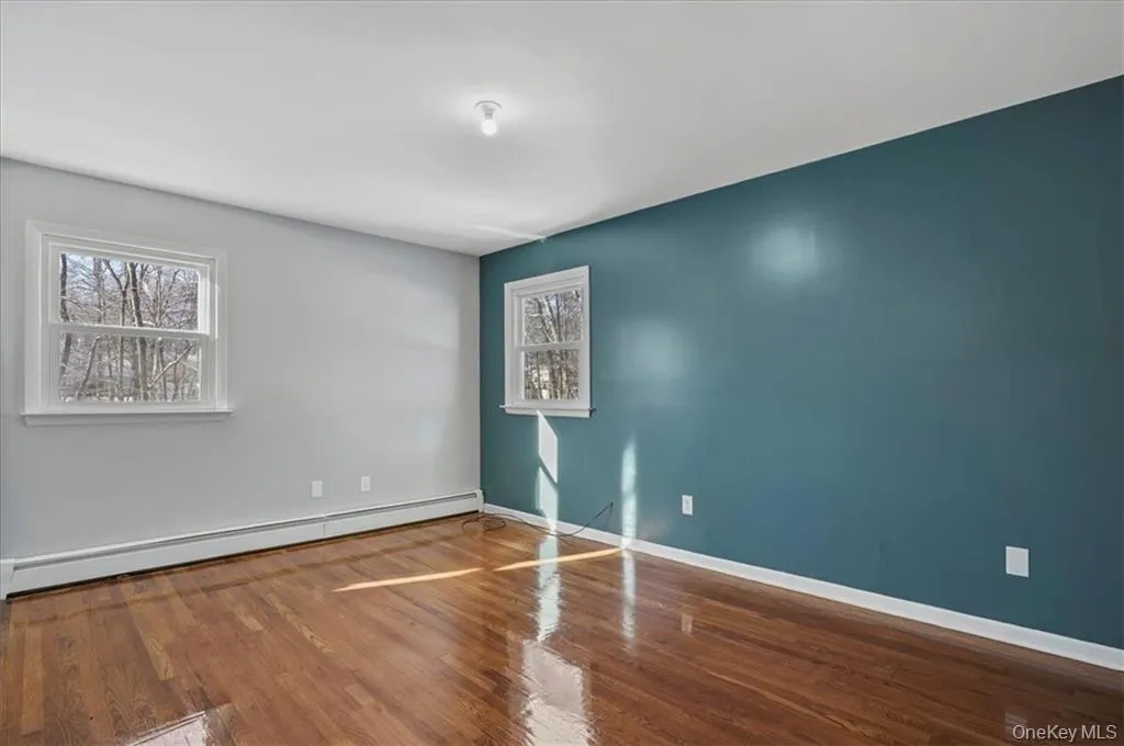 Spare room with wood finished floors and baseboard heating Spare room with wood finished floors and baseboard heating
