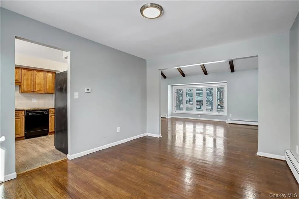 Spare room featuring beamed ceiling, dark wood finished floors, and a baseboard radiator Spare room featuring beamed ceiling, dark wood finished floors, and a baseboard radiator