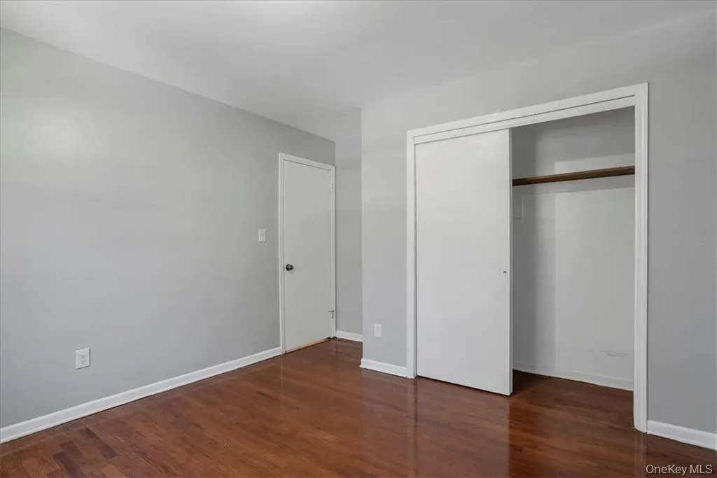 Unfurnished bedroom featuring dark wood-style floors and a closet Unfurnished bedroom featuring dark wood-style floors and a closet