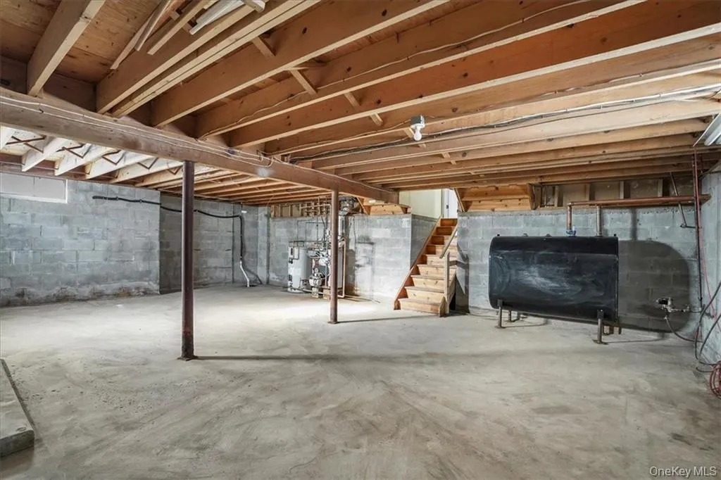 Unfinished below grade area featuring stairs, heating fuel, and water heater Unfinished below grade area featuring stairs, heating fuel, and water heater