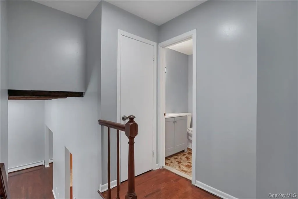 Hall with an upstairs landing, dark wood finished floors, and a baseboard heating unit Hall with an upstairs landing, dark wood finished floors, and a baseboard heating unit