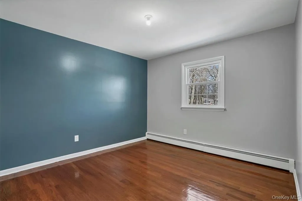 Unfurnished room with a baseboard heating unit and dark wood-type flooring Unfurnished room with a baseboard heating unit and dark wood-type flooring